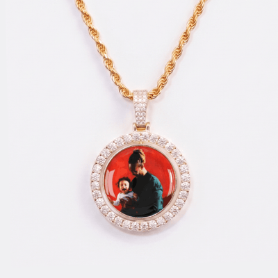 The front side of CRNCY's Double Sided Photo Pendant with a 14k gold finish. The front side features prong-set diamonds around the photo and on the bale. The front side shows the first photo choice.