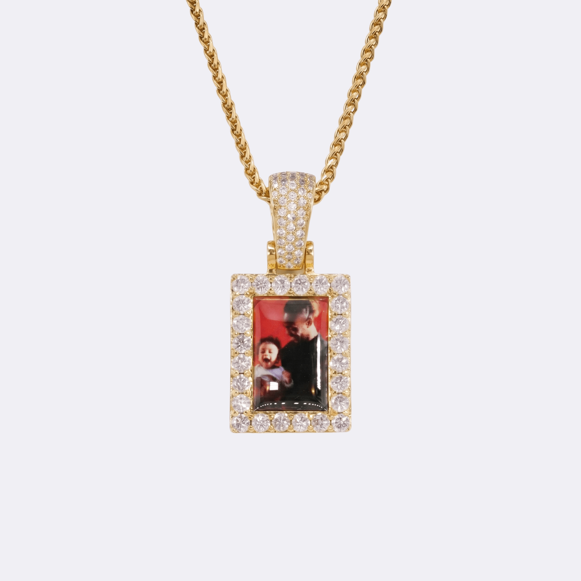 The front side of CRNCY's Small Framed Photo Pendant with a 14k gold finish. The front side features prong-set diamonds around the photo and on the bale. The front side shows the customer's photo choice.