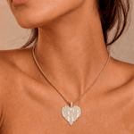 Female model wearing CRNCY's Nana Heart Photo Pendant with a 14k gold finish and a 16 inch length necklace.