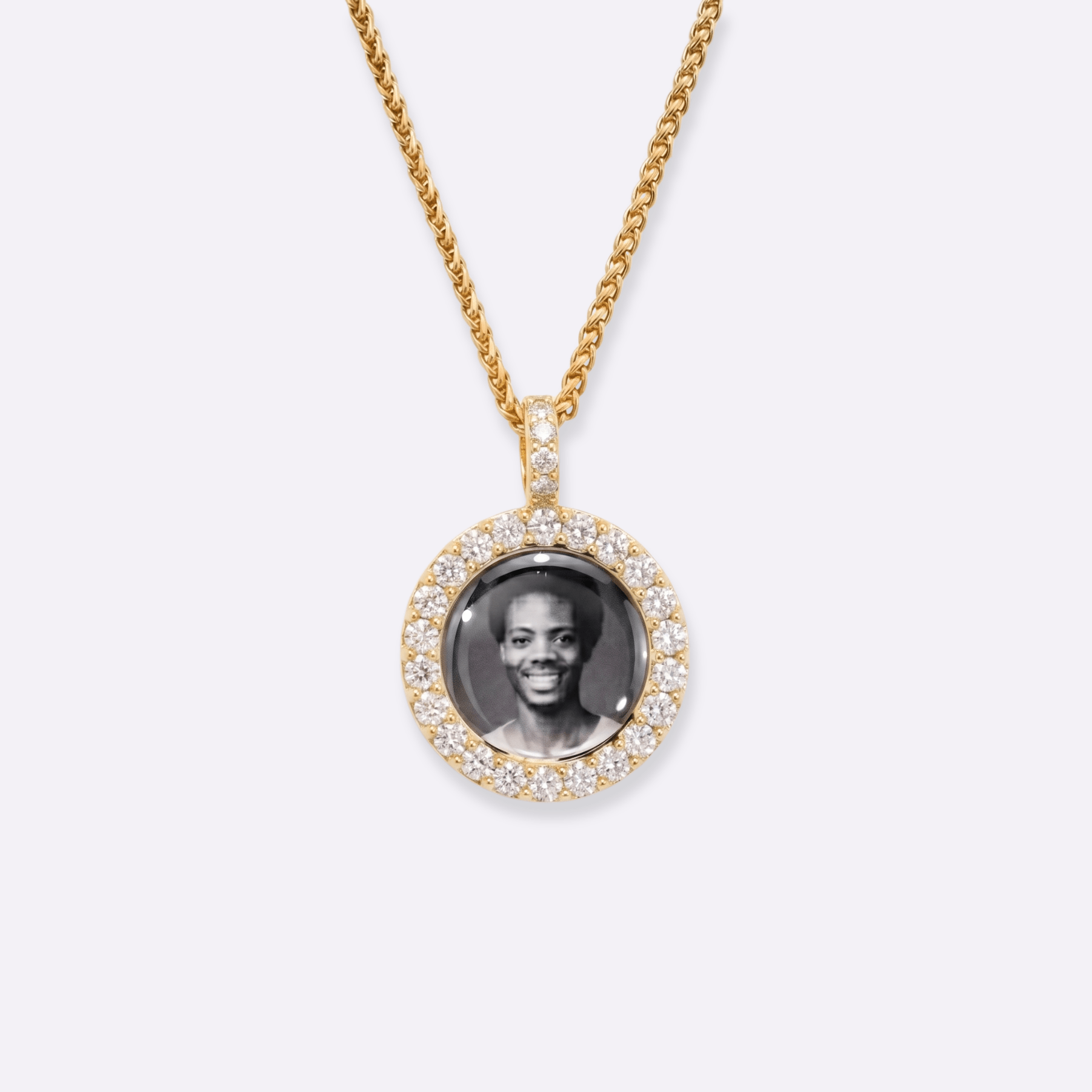 The front side of CRNCY's Mini Iced Photo Pendant with a 14k gold finish. The front side features prong-set diamonds around the photo and on the bale. The front side shows the customer's photo selection.