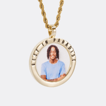 The front side of CRNCY's Rest In Paradise Photo Pendant with a 14k gold finish. The front side features a polished border around the photo. "Rest In Paradise" is engraved on the upper half of the photo pendant, filled with black jewelry enamel. The front side shows the customer's photo selection. 
